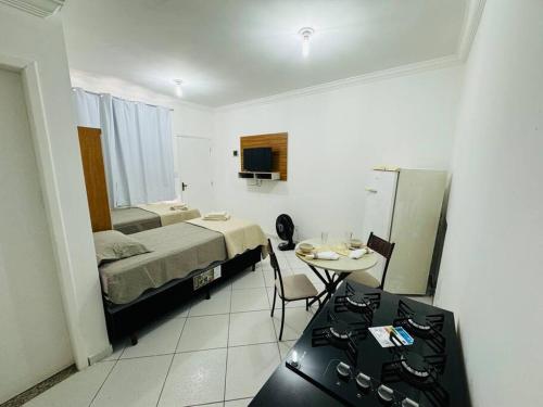 a hotel room with a bed and a table and a room at Kitnet cheia de estilo, ipatinga mg in Ipatinga