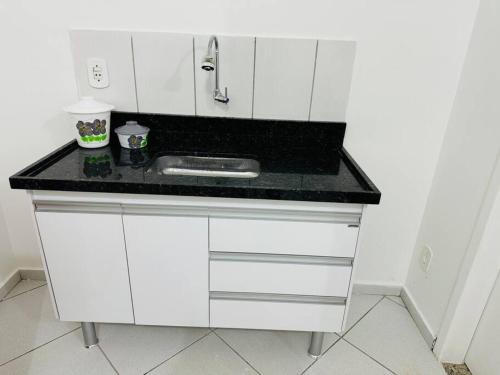 a white kitchen with a sink and a counter at Kitnet cheia de estilo, ipatinga mg in Ipatinga