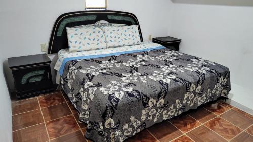 a bedroom with a bed with a black and white comforter at Cómodo y acogedor departamento in Oaxaca City