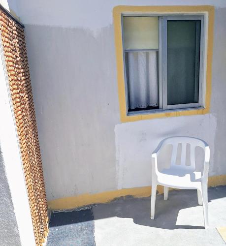 a white chair sitting in front of a window at Casa dos pais in Crato