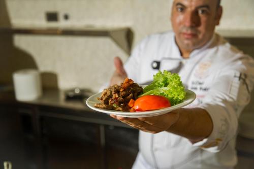 a chef holding a plate of food in a kitchen at Faraj Almadina Hotel in Al Madinah