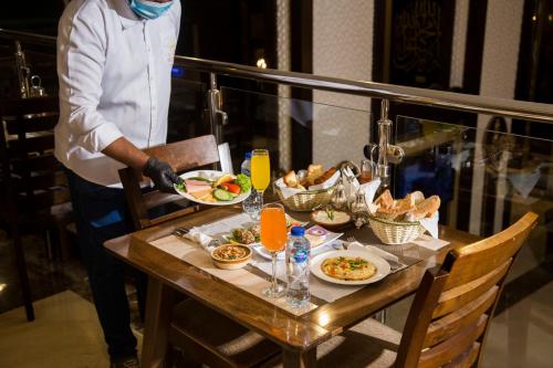 a man holding a plate of food on a table at Faraj Almadina Hotel in Al Madinah