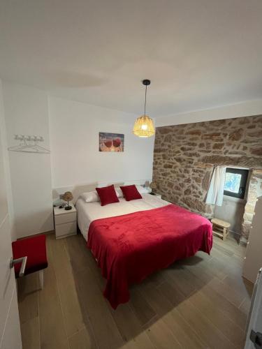 a bedroom with a large bed with a red blanket at Ca l'Artigalas in Cardona