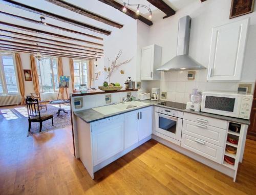 une cuisine avec des armoires blanches et un four à plaques de cuisson dans l'établissement Le Loft Gambetta -Poitiers Centre- LaConciergerie, à Poitiers