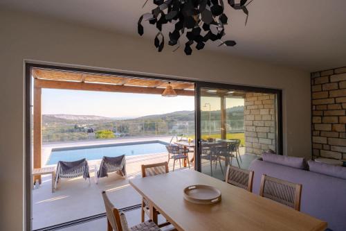 a living room with a table and a view of a pool at Aggel's Infinity View Villa - private pool in Káto Episkopí