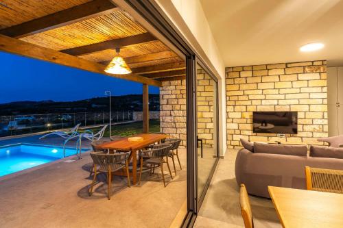 a patio with a table and a couch and a pool at Aggel's Infinity View Villa - private pool in Káto Episkopí