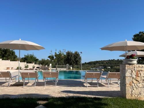 a group of chairs and umbrellas next to a pool at Casa Vacanze 'La Quercia' in Cisternino