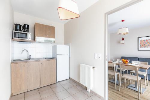 a kitchen and dining room with a table in a room at Appart'City Confort Orléans in Orléans