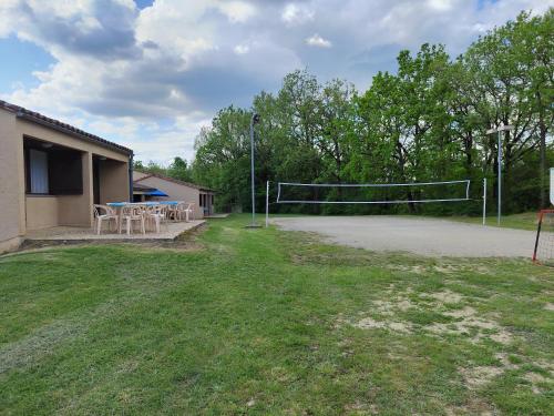 an outdoor volleyball court with tables and chairs in a yard at Village Bord de Ciel in Caylus