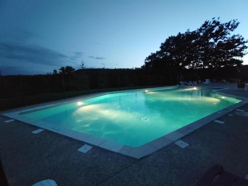 a large swimming pool with lights in a parking lot at Village Bord de Ciel in Caylus