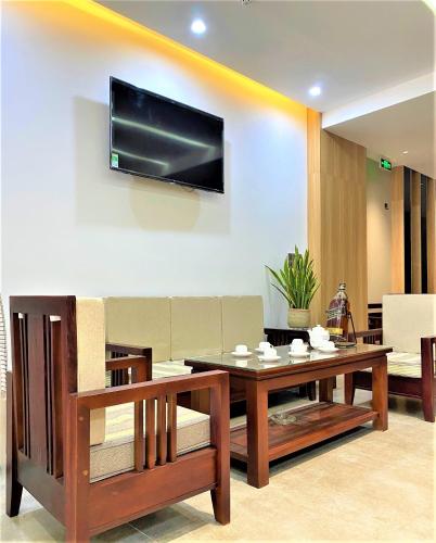 a living room with a table and a tv on a wall at Khách Sạn LUCIEN HOTEL Quy Nhơn in Quy Nhon