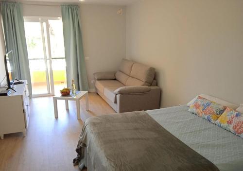 a bedroom with a bed and a couch and a chair at Estudio en Torres del Sol en lado del mar in Arona