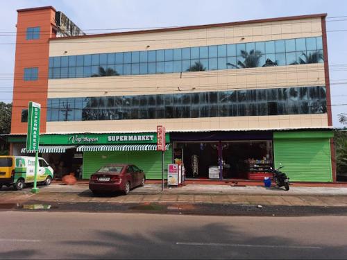 a green building with a car parked in front of it at Kandengath Residency and Lodge in Trichūr