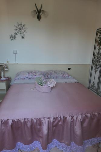 a bed with a pink bed skirt on it at B&B Luna in Castelvetro di Modena