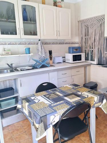 a kitchen with a table with chairs and a microwave at Casa dos pais in Crato