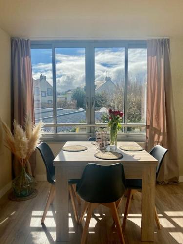 une table de salle à manger avec des chaises et une grande fenêtre dans l'établissement Escale sur le port de Dahouet avec vue sur mer, à Pléneuf-Val-André