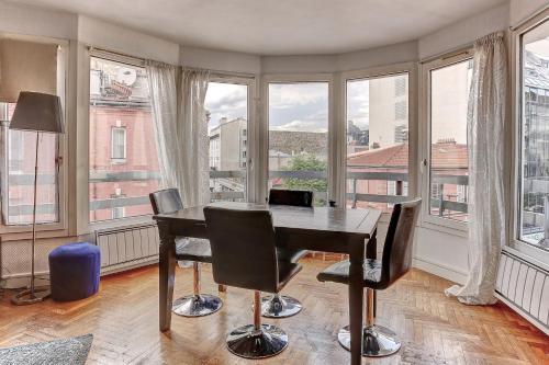 Cette chambre comprend un bureau, des chaises et des fenêtres. dans l'établissement Le Charlemagne- Boulogne, à Boulogne-Billancourt