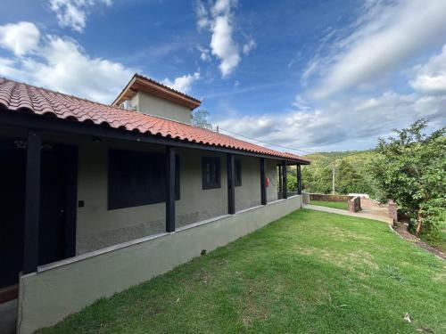 a house with a grass yard next to a building at Pousada Villa Tropea - Fazenda Chapadão in Serra Negra