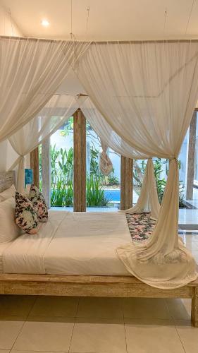 1 cama con dosel en una habitación con ventana en Villa Tilumanis, en Canggu