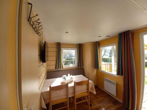 un pequeño comedor con mesa y 2 ventanas en Mobilhome EUROPA PARK, en Boofzheim