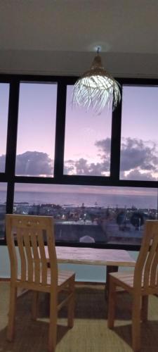 two chairs and a table in front of a window at Appartement Coucher de Soleil uniquement les familles in Oualidia