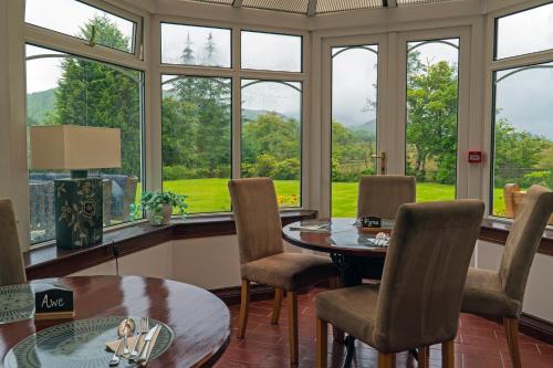 a dining room with windows and a table and chairs at Killean Farmhouse B&B in Inveraray