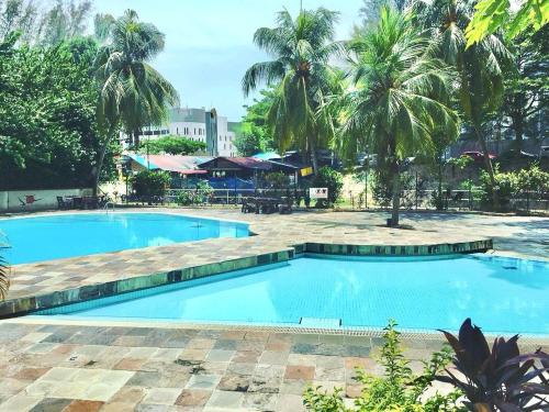 una grande piscina con palme sullo sfondo di De One Homestay Bayu Emas Near Beach a Batu Ferringhi