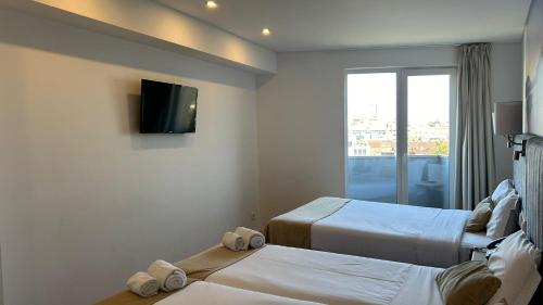 a hotel room with two beds and a flat screen tv at Hotel Porto Interface Trindade By Kavia in Porto