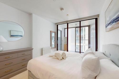 a white bedroom with a large bed and a mirror at 1Bed Flat with city views - 1min walk to tube station in London
