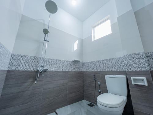 a white bathroom with a toilet and a window at Eden Sea View in Talpe