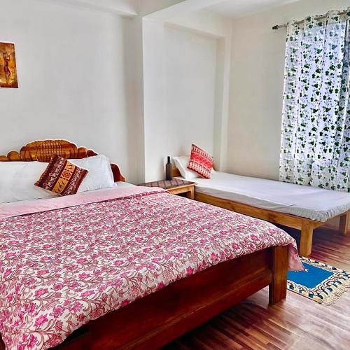 a bedroom with two beds and a window at Tourbix Mirik in Mirik