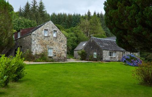 an old stone house with a green yard at Killean Farmhouse Cottages in Auchnangoul