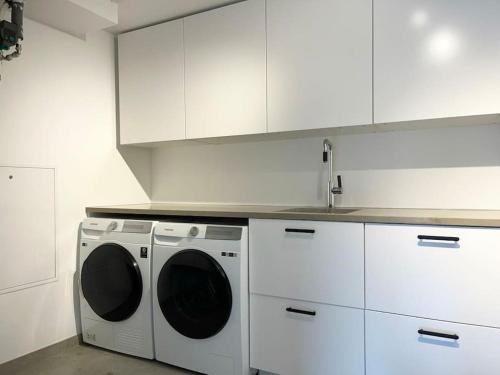 a kitchen with a washing machine and a sink at Exklusiv villa med sjöutsikt och egen brygga in Nacka