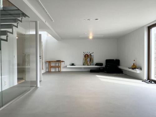 a living room with white walls and a white floor at Exklusiv villa med sjöutsikt och egen brygga in Nacka