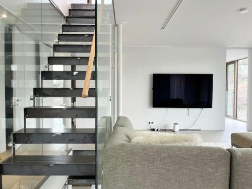 a staircase in a living room with a couch and a tv at Exklusiv villa med sjöutsikt och egen brygga in Nacka
