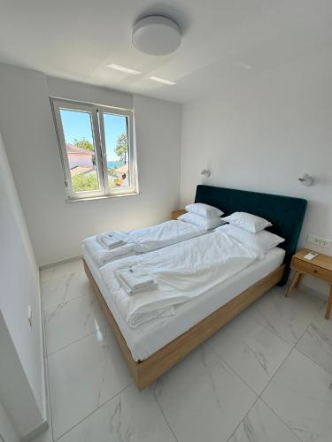 a bed in a white room with a window at Beautiful new PalmTree Apartments in Vir