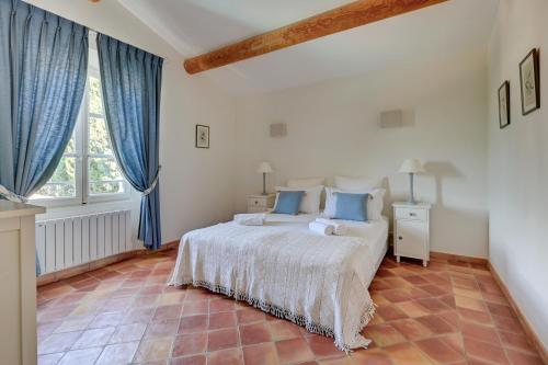 une chambre avec un grand lit avec des rideaux bleus dans l'établissement LE MAS DU GOUVERNEUR, à Saint-Rémy-de-Provence