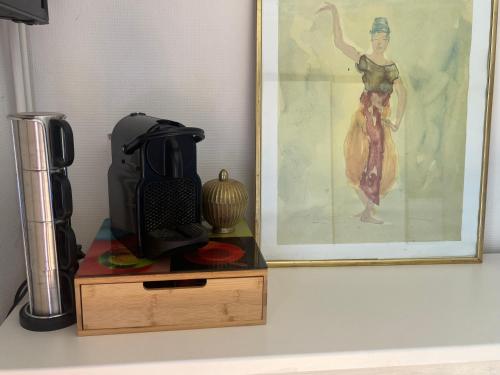 un mixeur noir assis sur un support en bois à côté d'un tableau dans l'établissement Deux grandes chambres en rez-de-jardin, à Montayral