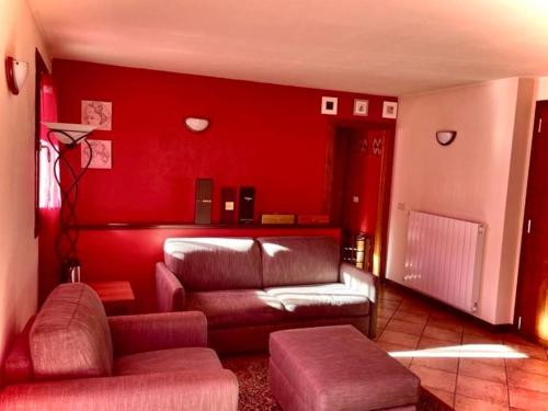 a living room with a couch and a red wall at Villetta Gaia in Vezza dʼOglio