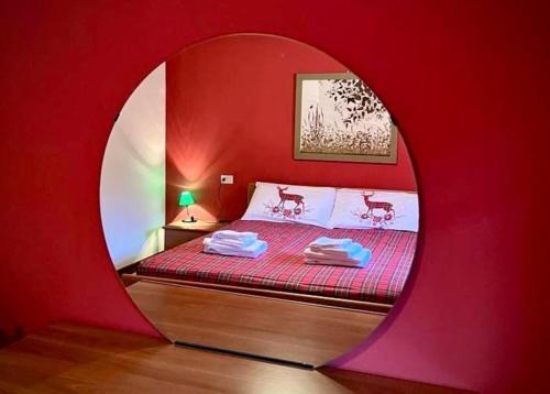a red bedroom with a bed with a round mirror at Villetta Gaia in Vezza dʼOglio