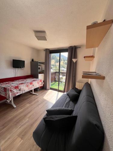 - un salon avec un canapé noir et une grande fenêtre dans l'établissement Appartement 6/8 couchages La Foux d'Allos, à La Foux