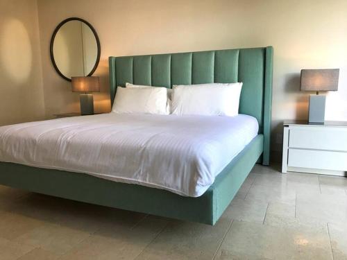 Boca de Río HatoにあるElegante apartamento de 2 habitacionesの緑のヘッドボードと鏡が付いた大きなベッド