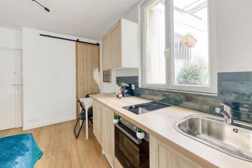 a kitchen with a sink and a window at Le Clichy Chic in Clichy