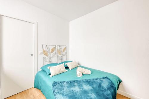 a bedroom with a blue bed with two pillows at Le Clichy Chic in Clichy