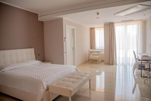 a white bedroom with a bed and a table and chairs at Hotel Ristorante Europa in Venticano