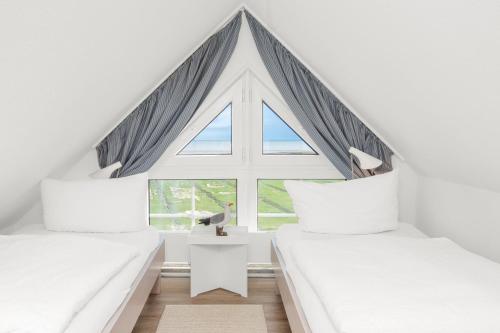 Dos camas en una habitación con una gran ventana. en Residenz am Meer 24C Graugans, en Juist