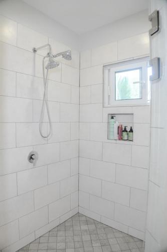 a white bathroom with a shower with a window at Blue Paradise House Roatan in Roatan