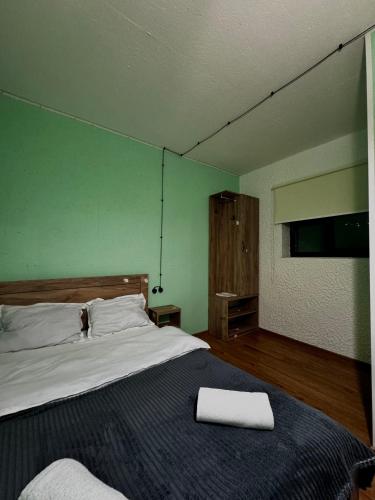 a bedroom with a large bed and a green wall at Hotel Pavilion Garden in Stepantsminda