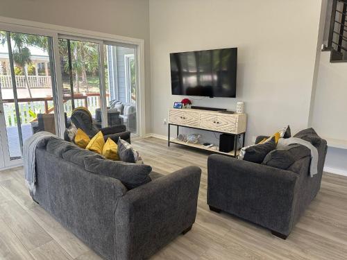 a living room with two couches and a flat screen tv at Blue Paradise House Roatan in Roatan