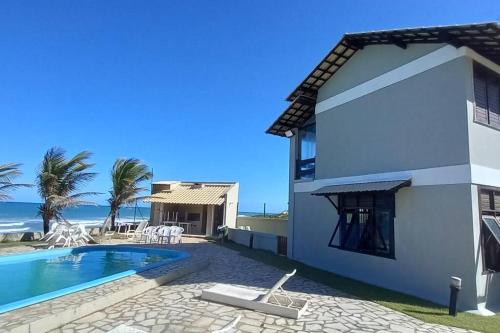 a villa with a swimming pool next to the ocean at Casa de praia Vista Mare Beira-mar in Barra de São Miguel